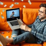 Person enjoying videos on laptop with money around.